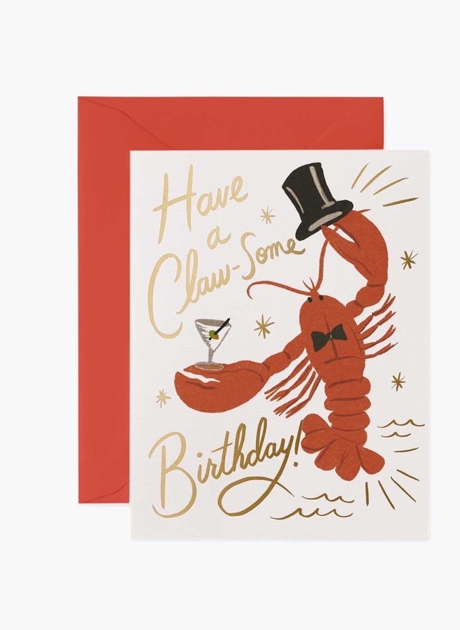 Födelsedagskort med en hummer i hög hatt och fluga som håller ett martiniglas, med texten Have a Claw-Some Birthday i guldfolie och rött kuvert